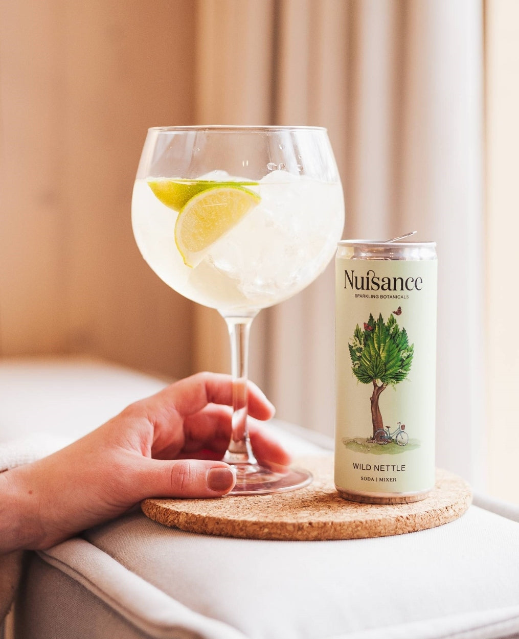 A woman holding a Cold glass of a refereshing cocktail of Gin and mix with a Premium Nettle and Elderflower botanical drink from Scotland-based drinks start-up brand Nuisance drinks