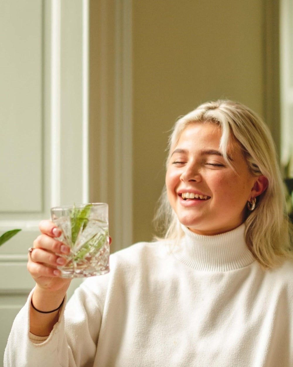 A women enjoying a glass of whiskey sour with a twist by topping it with a premium Nettle and Elderflower botanical soft drinks from Scotland-based drinks start-up brand Nuisance Drinks.