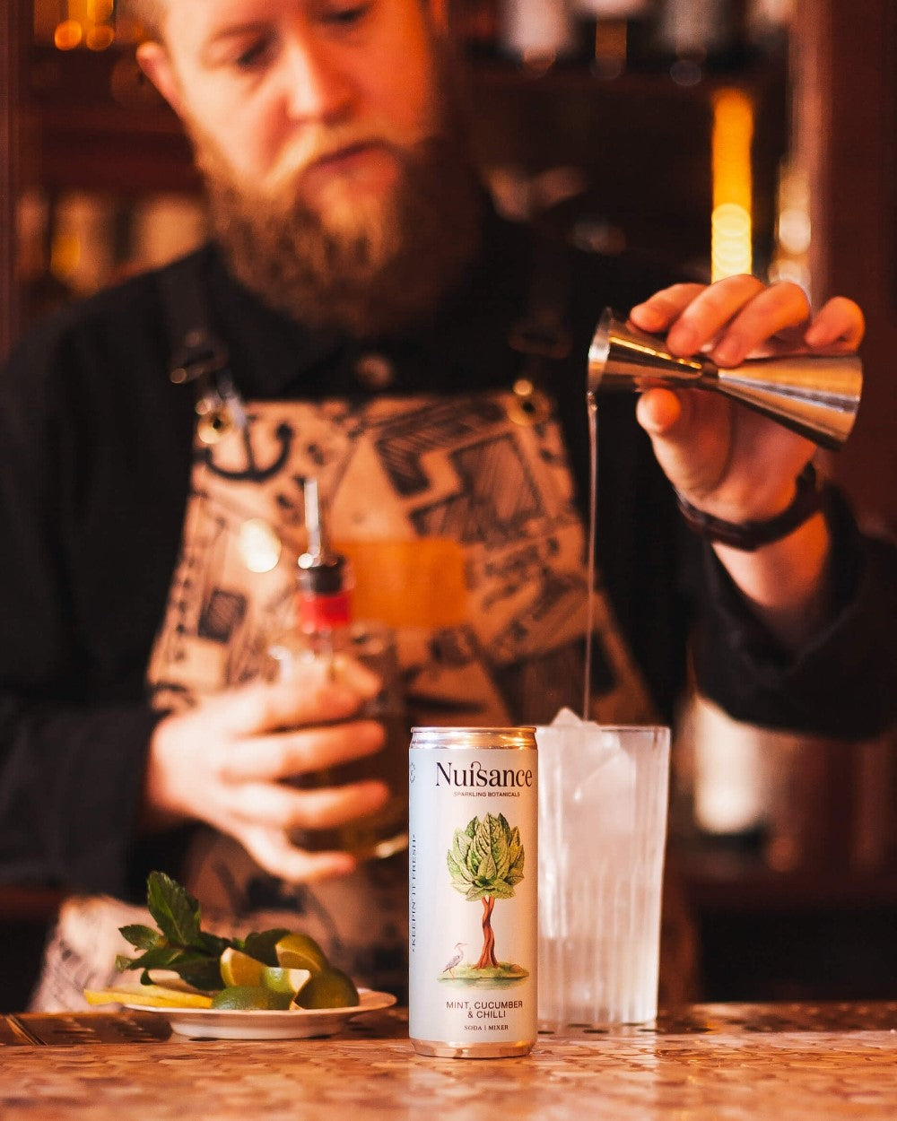 A Cocktail Barman making a cold cocktail of Tequila, Lime juice, sugar syrup and topping it with a refreshing can of premium Mint, Cucumber and Chilli botanical soft drink. from Scotland-based drinks start-up brand Nuisance drinks